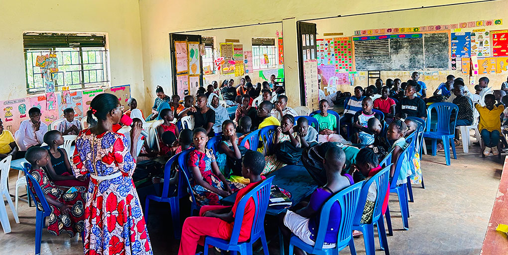 Young people sitting inside the classroom with the teacher during the Youth Leaders Camp 2025 in Uganda.