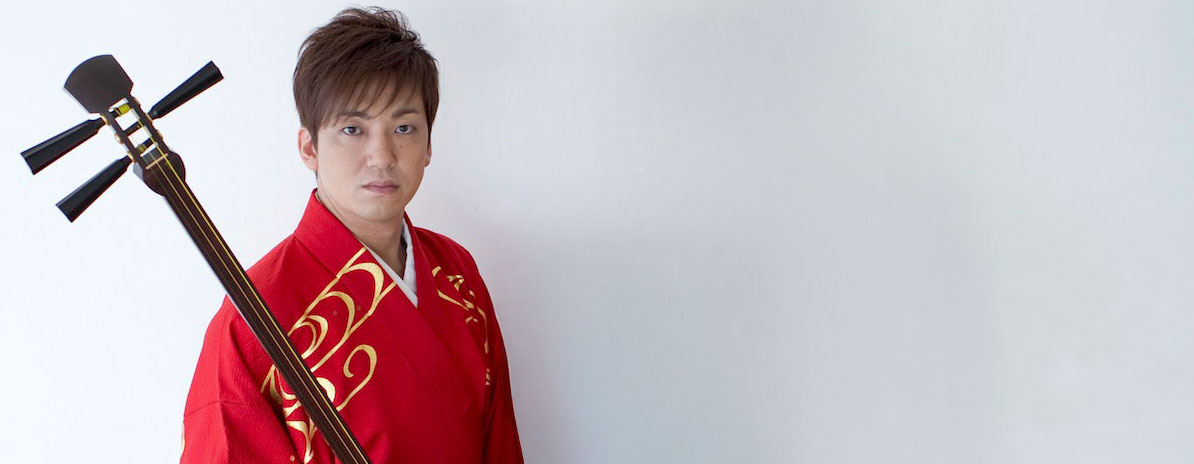 Non-Violence ambassador Kenichi Yoshida, a Japanese musician holding a traditional three-stringed instrument from northern Japan called Tsugaru-jamisen.